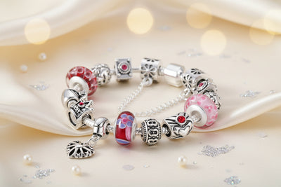 Murano-Glas Armband mit roten und rosa Glasperlen, Herz-Charms und filigranem Herz-Anhänger auf cremefarbenem Satin