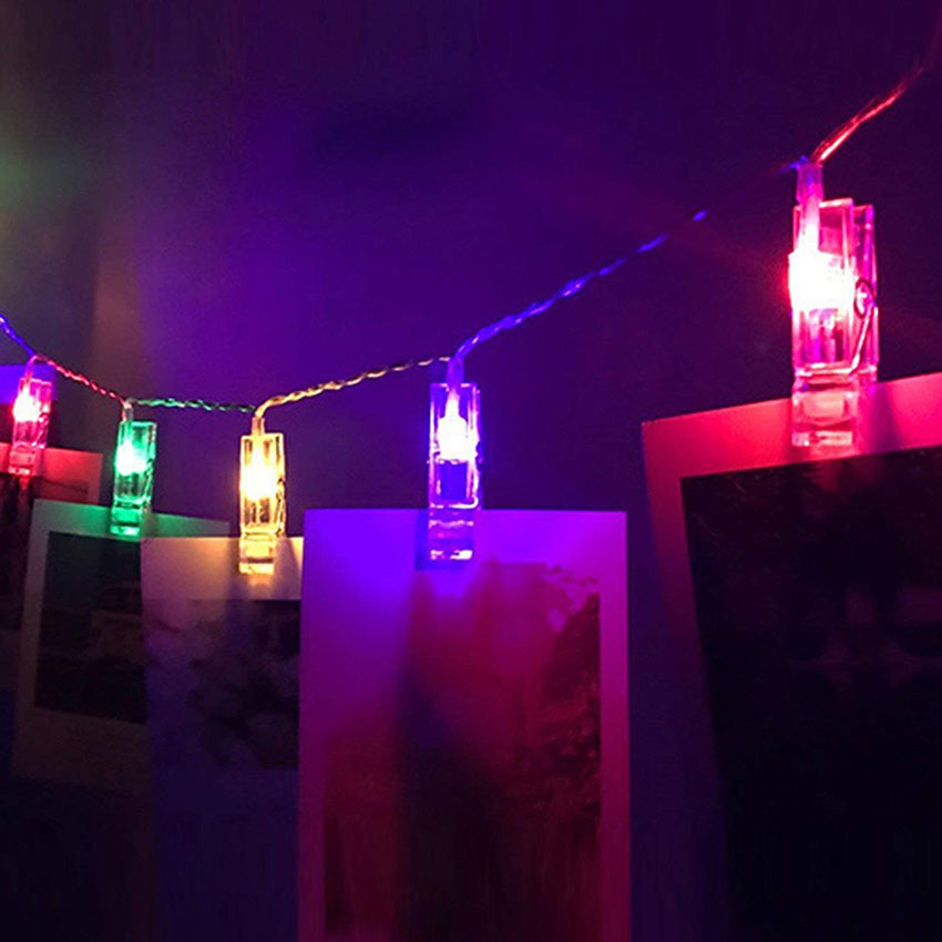 Detailaufnahme einer Foto Lichterkette LED in einem Schlafzimmer, Polaroids aufgehängt zwischen den Lichtern, sorgt für eine romantische Atmosphäre.