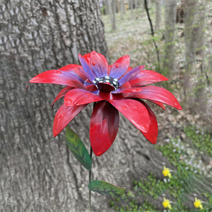 Roter Blumenstecker Metall aus Schmiedeeisen zwischen blühenden Rosen im Garten