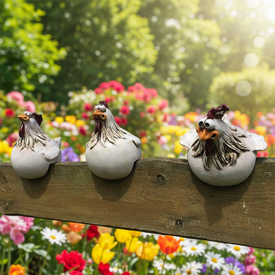 Gartenfigur Huhn im Dreierset auf dem Holzzaun vor bunten Blumen, drei weisse Hühnerfiguren mit Glupschaugen im Garten
