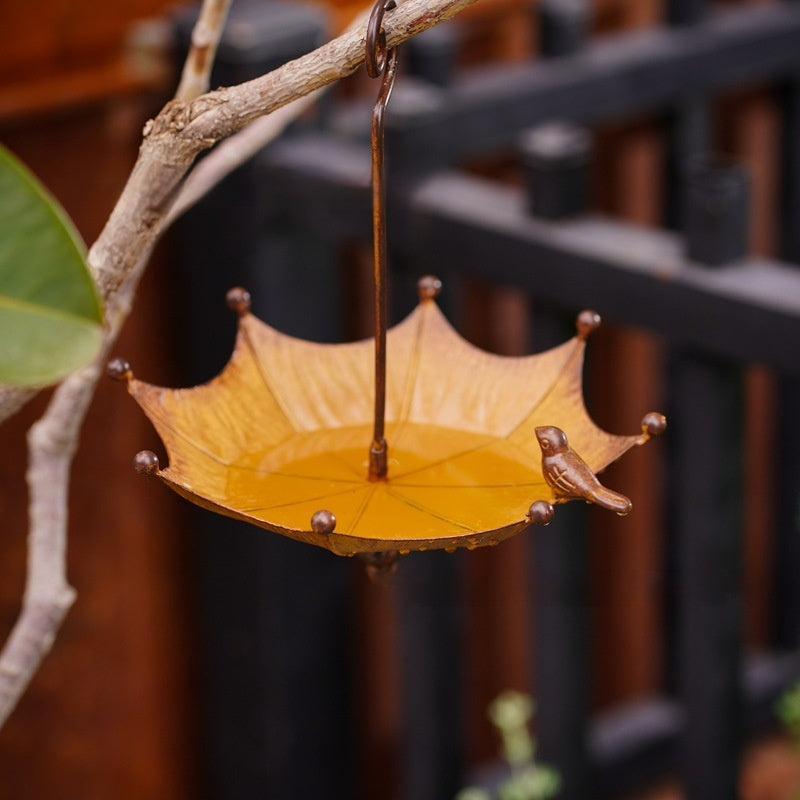 Vogelfutterspender im Regenschirm-Design aus Bronze-Metall mit Vogelfigur am Rand, Nahaufnahme