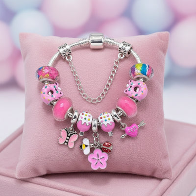 Charm-Armband in Rosa auf Samtkissen mit Donut-Perlen, Blüten-Anhänger und kleinem Schmetterling, als Geschenk für Mädchen