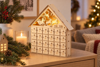 Holz-Adventskalender Weihnachtshaus HoHoHo mit leuchtendem Giebel auf einem Sideboard am Abend